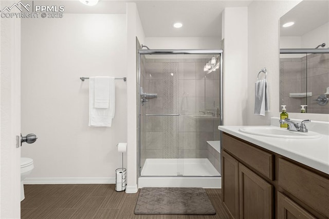 bathroom with a stall shower, recessed lighting, baseboards, toilet, and vanity