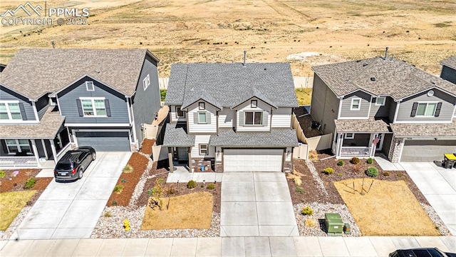 view of front of home featuring concrete driveway, a shingled roof, a residential view, and an attached garage