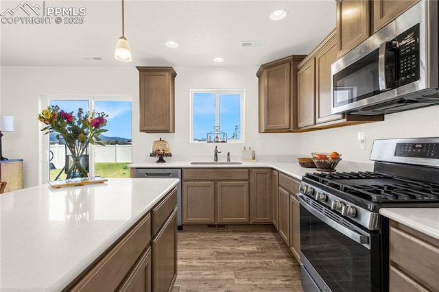 kitchen featuring visible vents, a sink, wood finished floors, light countertops, and appliances with stainless steel finishes