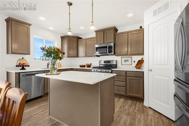 kitchen featuring wood finished floors, visible vents, light countertops, a center island, and appliances with stainless steel finishes