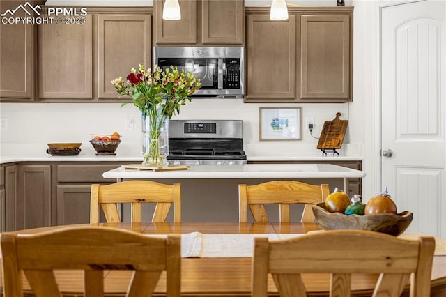 kitchen with light countertops, stainless steel appliances, and decorative light fixtures