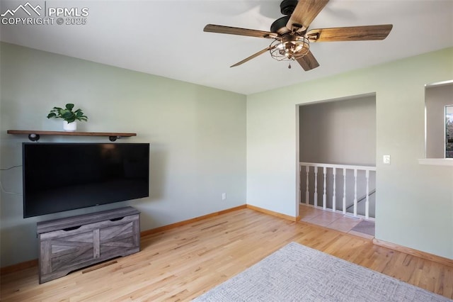 unfurnished living room featuring a ceiling fan, baseboards, and wood finished floors