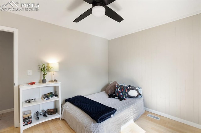 bedroom featuring a ceiling fan, visible vents, wood finished floors, and baseboards