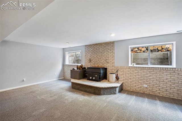 living area with a wood stove, carpet flooring, baseboards, and brick wall