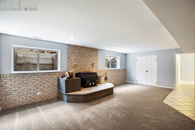 tiled living area featuring a wood stove, carpet flooring, and brick wall