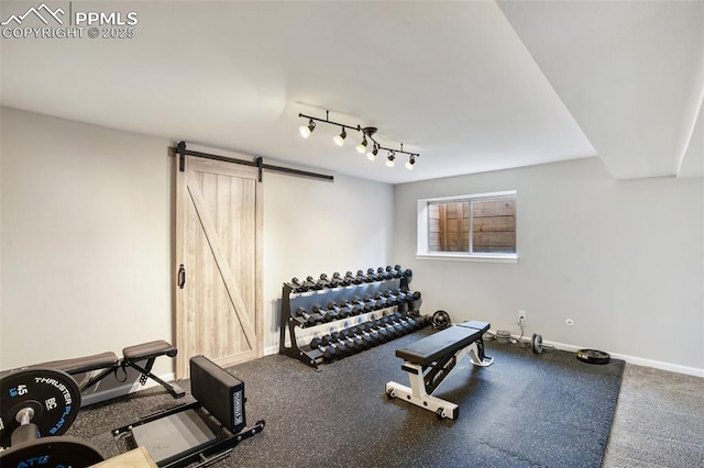 exercise room featuring a barn door and baseboards