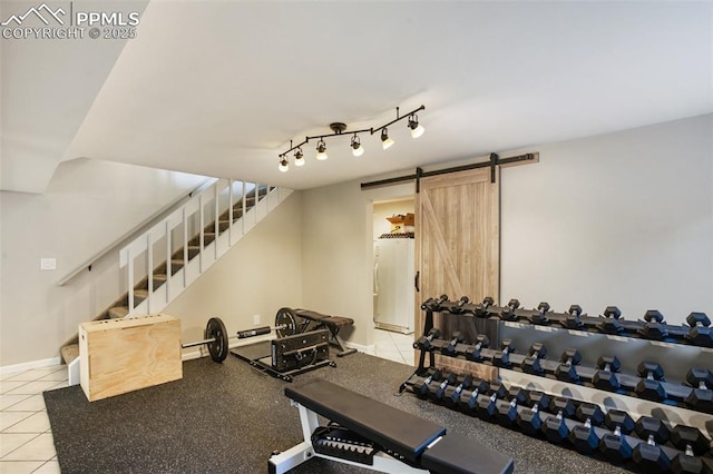 workout room featuring a barn door, baseboards, and light tile patterned floors