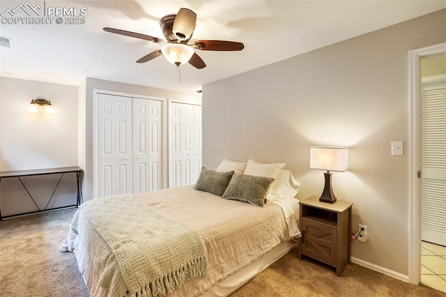 carpeted bedroom with baseboards, ceiling fan, multiple closets, and visible vents