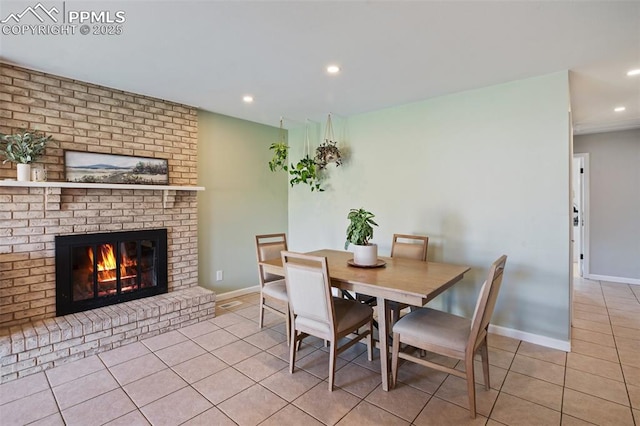 tiled dining room with baseboards, a brick fireplace, and recessed lighting
