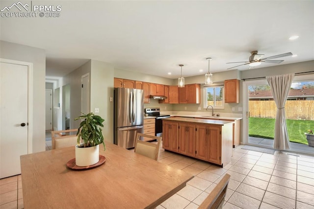 kitchen featuring a sink, light countertops, a center island, light tile patterned floors, and appliances with stainless steel finishes