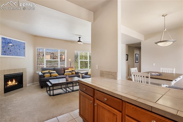 kitchen featuring tile counters, light colored carpet, ceiling fan, and open floor plan
