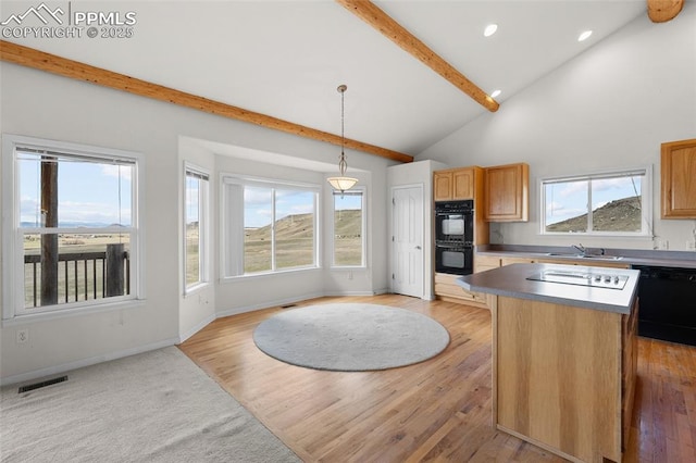 kitchen with visible vents, a kitchen island, beamed ceiling, a sink, and black appliances