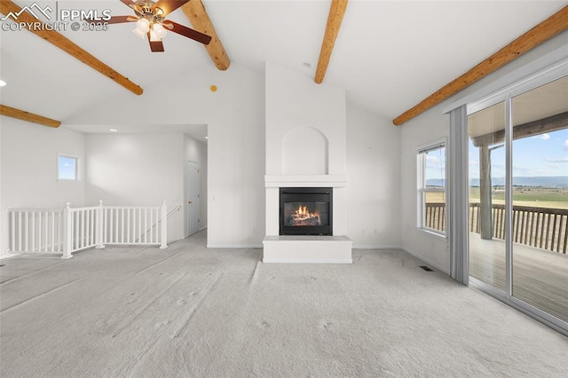 unfurnished living room with carpet floors, a ceiling fan, and beamed ceiling