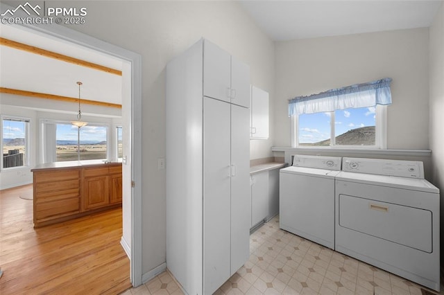 laundry area with separate washer and dryer, plenty of natural light, light wood finished floors, and cabinet space