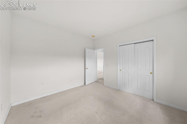 unfurnished bedroom featuring carpet floors, baseboards, and a closet