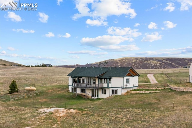 rear view of property featuring a yard, a deck with mountain view, and fence
