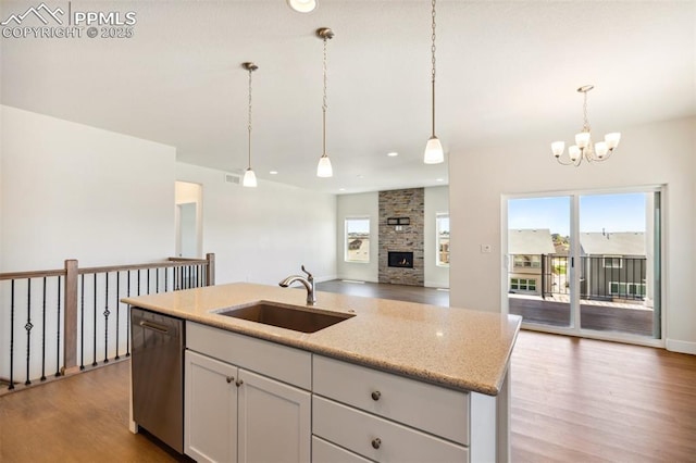 kitchen featuring a sink, stainless steel dishwasher, open floor plan, a chandelier, and wood finished floors