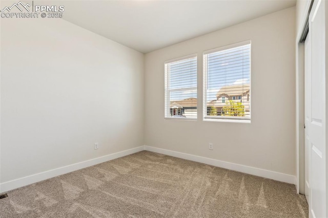 empty room featuring light colored carpet and baseboards