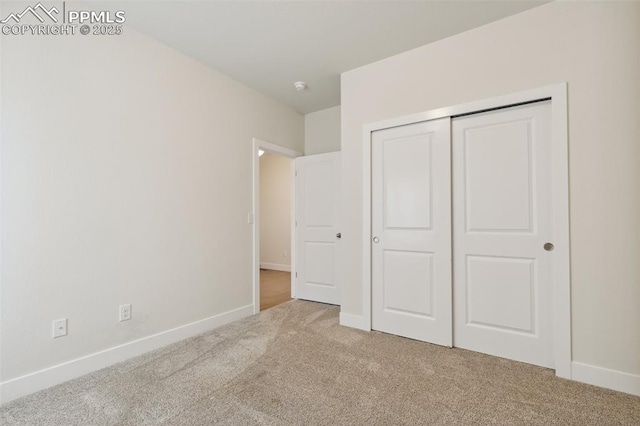 unfurnished bedroom with carpet floors, baseboards, and a closet