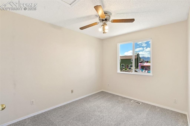 carpeted spare room featuring visible vents, a ceiling fan, baseboards, and a textured ceiling