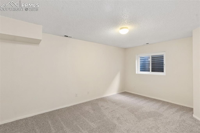 carpeted empty room featuring a textured ceiling, visible vents, and baseboards