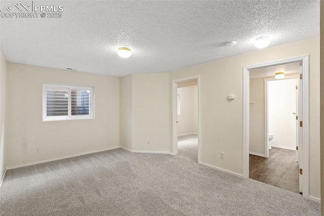 unfurnished room with carpet flooring, a textured ceiling, and baseboards