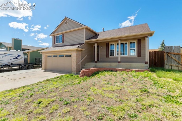 split level home featuring fence, roof with shingles, a garage, a porch, and concrete driveway