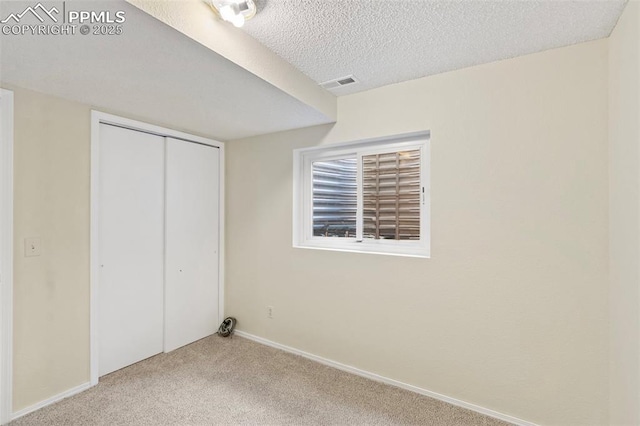 unfurnished bedroom with a textured ceiling, visible vents, baseboards, a closet, and carpet flooring