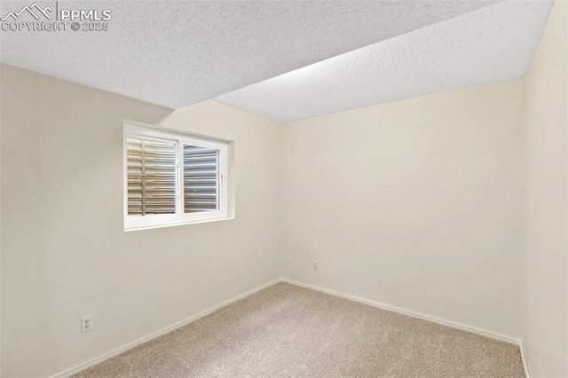 unfurnished room with a textured ceiling, baseboards, and carpet
