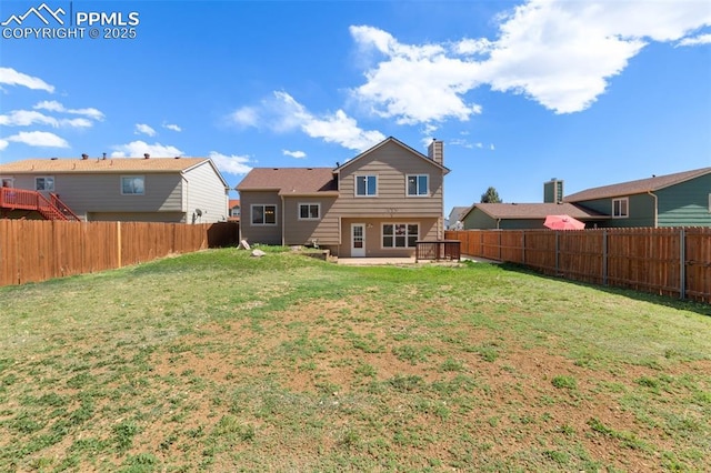 rear view of house with a lawn, a fenced backyard, a patio area, and a chimney
