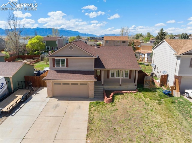 traditional home with a garage, fence, a mountain view, and brick siding