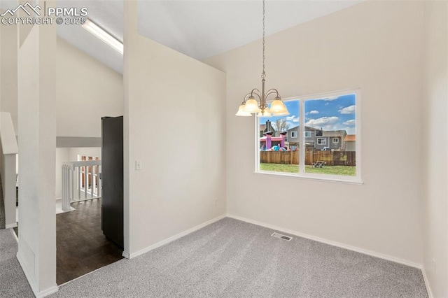 spare room featuring carpet, vaulted ceiling, and a notable chandelier