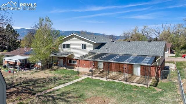 rear view of property with roof with shingles, fence, brick siding, a gate, and a mountain view