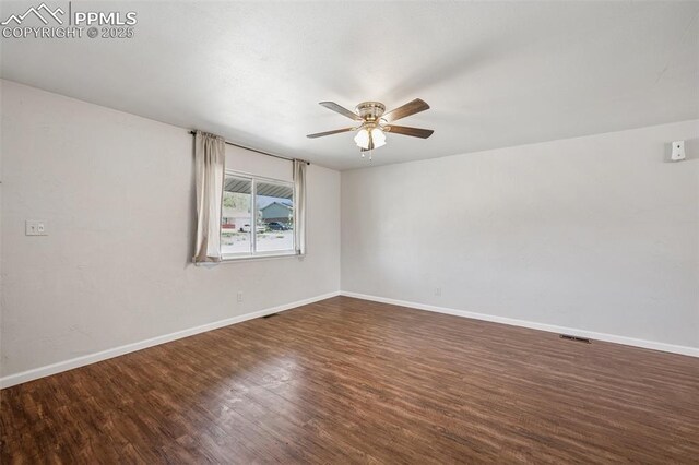 spare room with baseboards, a ceiling fan, wood finished floors, and visible vents