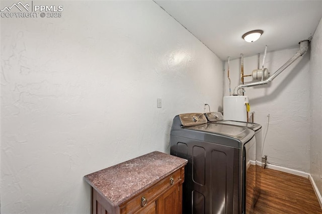 laundry area with dark wood-style flooring, cabinet space, baseboards, water heater, and washer and clothes dryer
