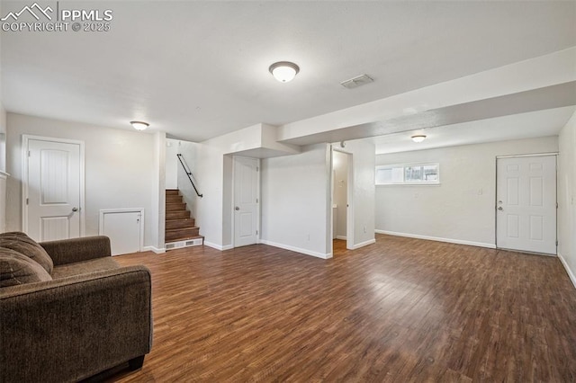 living room featuring baseboards, wood finished floors, and stairway