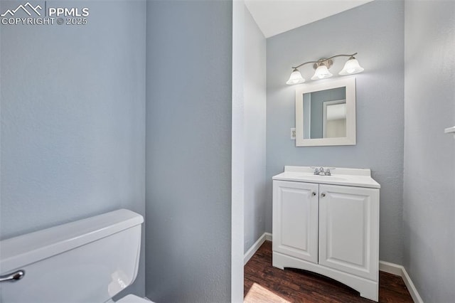 bathroom with baseboards, wood finished floors, toilet, and vanity