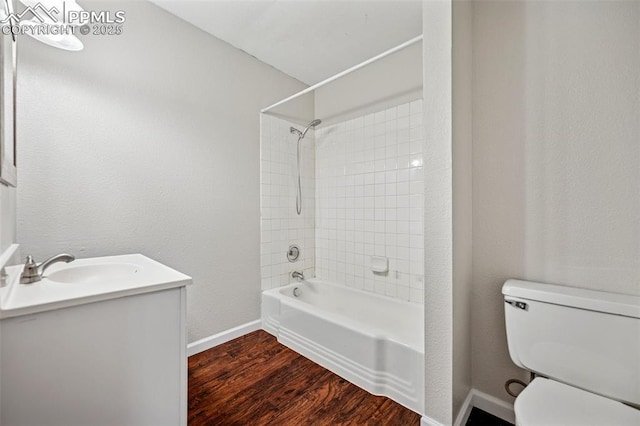 bathroom featuring vanity, wood finished floors, toilet, baseboards, and washtub / shower combination