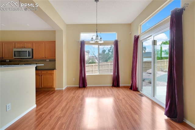4282 Thornbury Way, Colorado Springs, CO 80922 - unfurnished dining area with light wood finished floors, a chandelier, and plenty of natural light