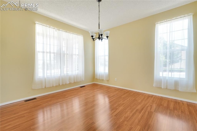 4282 Thornbury Way, Colorado Springs, CO 80922 - empty room with a chandelier, plenty of natural light, wood finished floors, a textured ceiling, and baseboards