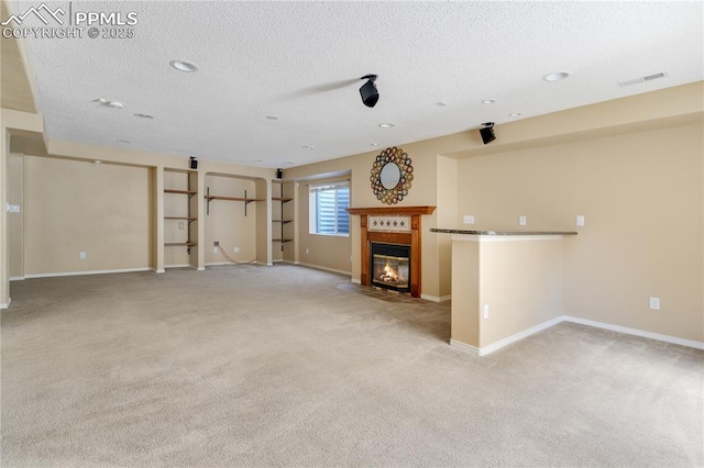4282 Thornbury Way, Colorado Springs, CO 80922 - unfurnished living room featuring light colored carpet, a textured ceiling, a fireplace with flush hearth, baseboards, and recessed lighting