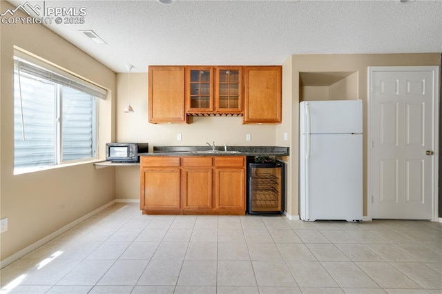 4282 Thornbury Way, Colorado Springs, CO 80922 - kitchen featuring freestanding refrigerator, beverage cooler, brown cabinetry, dark countertops, and a textured ceiling