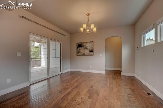 275 Eclipse Dr, Colorado Springs, CO 80905 - spare room with arched walkways, wood finished floors, a chandelier, and baseboards