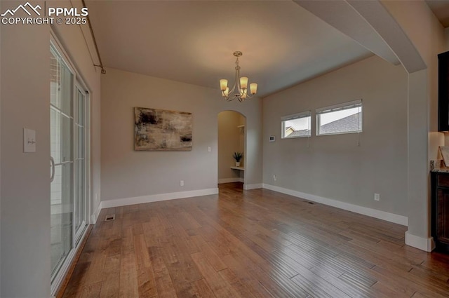 275 Eclipse Dr, Colorado Springs, CO 80905 - unfurnished dining area featuring arched walkways, wood finished floors, baseboards, and a chandelier