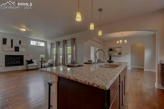 275 Eclipse Dr, Colorado Springs, CO 80905 - kitchen featuring a sink, arched walkways, hardwood / wood-style floors, a high end fireplace, and light stone countertops