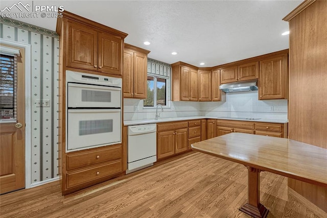 10 Gold Coin Ct, Colorado Springs, CO 80919 - kitchen featuring decorative backsplash, white appliances, light wood-type flooring, light countertops, and under cabinet range hood