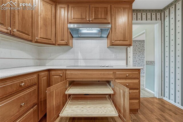 10 Gold Coin Ct, Colorado Springs, CO 80919 - kitchen featuring wallpapered walls, extractor fan, brown cabinetry, and wood finished floors