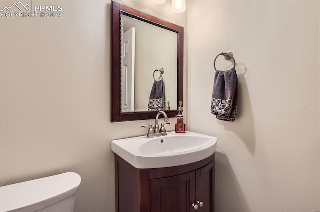 half bathroom featuring vanity and toilet