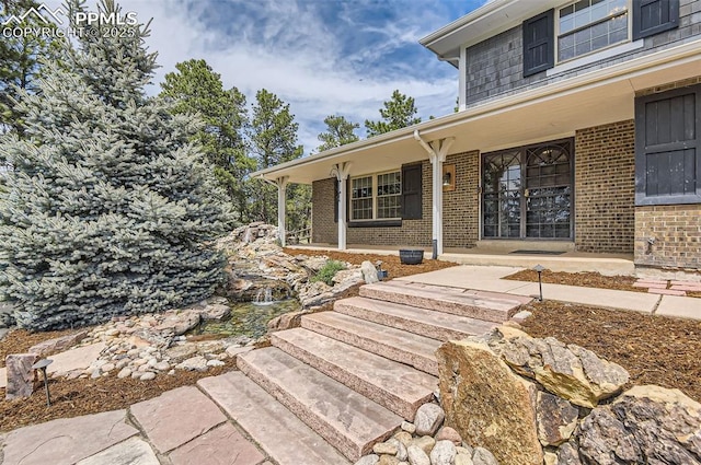 property entrance with a porch and brick siding