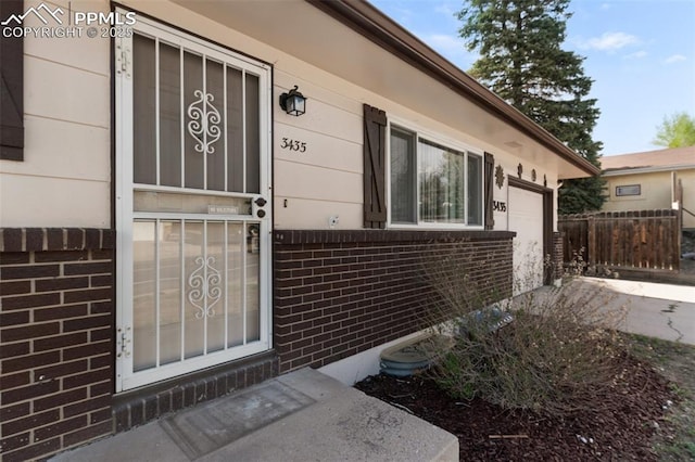 3435 Montebello Dr, Colorado Springs, CO 80918 - property entrance featuring brick siding, an attached garage, fence, and driveway